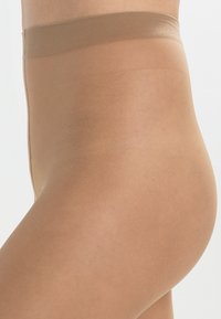 Beige, hochtaillierte Strumpfhose mit einer glatten, transparenten Textur. Sie verfügt über einen weichen, elastischen Bund für Komfort und einen eng anliegenden Sitz um die Taille.
