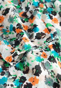 Tejido floral con base blanca, que presenta flores vibrantes en azul, naranja, verde y negro; textura ligera y suave, con un diseño fluido.