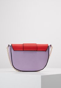 Fialová syntetická kabelka s červeným umělým koženým klopou a zlatým řetízkem. Zaoblený tvar s kontrastním černým okrajem.