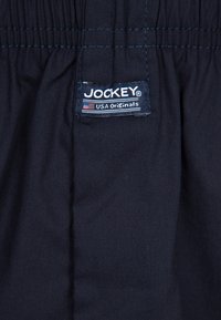 Marinblå shorts med elastisk midja. En etikett med "JOCKEY" och "USA Originals" är tydligt synlig på midjan.