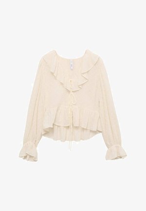 Cream-colored blouse with a ruffled neckline, long sleeves with flared cuffs, and a tiered hem. Fabric features subtle polka dots.