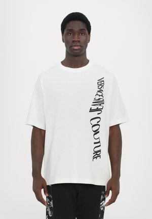 Hvid bomulds t-shirt med et sort vertikalt grafisk print på venstre side, korte ærmer og rund hals.
