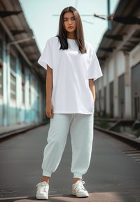 T-shirt bianca oversize, pantaloni jogger azzurri chiari e sneakers bianche. Tessuto morbido, vestibilità rilassata, con caviglie a polsino sui pantaloni jogger.