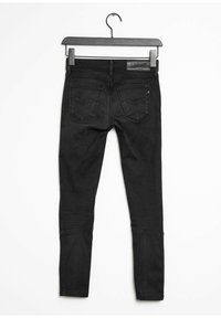 Svarta skinny jeans hängande från en svart galge. Funktionsdetaljer inkluderar en femfickedesign, texturerad tyg och sydda detaljer på bakfickorna.