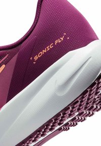 Scarpa sportiva viola con tomaia testurizzata, suola bianca e branding arancione "SONIC FLY". Presenta un design curvo e una suola decorata.