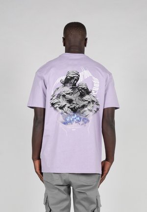 Lys lilla bomull t-skjorte med et grafisk trykk på baksiden av to figurer, omgitt av et blått og hvitt abstrakt design.