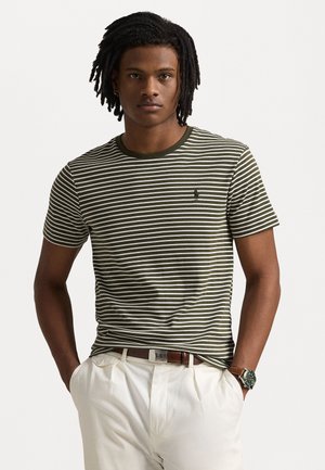 Camiseta de rayas verdes y blancas con cuello redondo y mangas cortas, que presenta un pequeño logo en el pecho. Tejido de algodón texturizado.