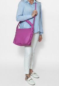 Borsa a tracolla in pelle viola con manico intrecciato, forma rettangolare, superficie liscia e un ampio scomparto principale.