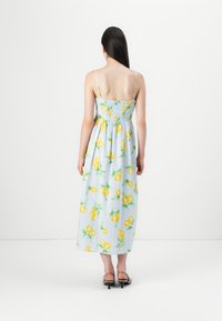 Blomstrete maxikjole med lyseblå bakgrunn som har gule sitronmønstre. Justerbare tynne stropper og detaljert smock-bol.