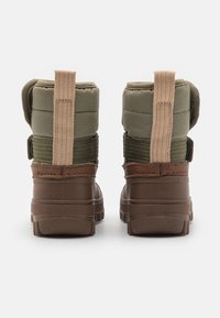 Hnědé voděodolné boty s prošívaným olivově zeleným textilním svrškem, hnědými látkovými akcenty a poutky pro snadné obouvání. Odolné gumové podrážky.