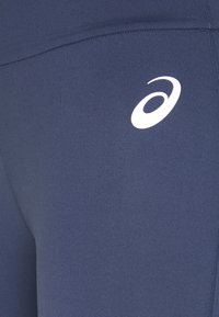 Leggings blu navy realizzati in tessuto elastico e liscio. Presentano un logo Asics bianco sul lato sinistro e cuciture piatte per il comfort.