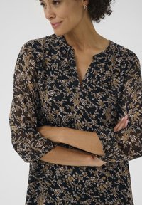Schwarze Bluse mit floralem Muster aus transparenter Stoff, mit einem Kragen und gerafften Ärmeln, in Gold- und Hellrosa-Tönen.