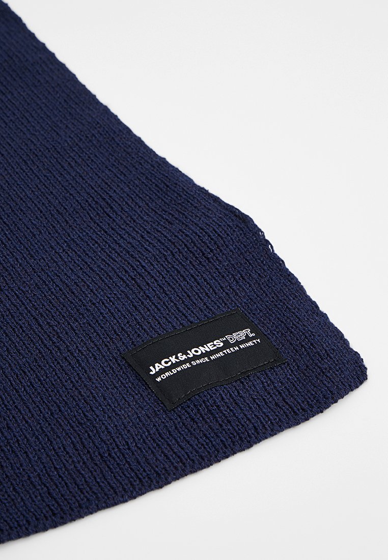 Marineblaue gestrickte Schal mit strukturierter Optik und einem schwarzen Etikett mit weißem Text, darauf steht "JACK & JONES DEPT." und Markeninformationen.