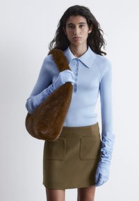 Hellblau gestreiftes Langarmoberteil mit Kragen und Knopfverschluss, kombiniert mit einem engen olivgrünen Minirock. Braune Fell-Schultertasche. Blaue Handschuhe.