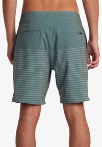 Bañadores para hombre en color teal con rayas horizontales blancas. Cuenta con dos bolsillos traseros y una tela suave y ligera.