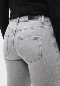 Γκρι ξεθωριασμένο τζιν με στενή εφαρμογή, με πίσω τσέπες, δερμάτινο ταμπελάκι με λογότυπο και αντίθετες ραφές.