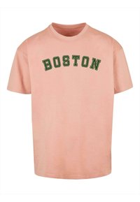 Roze katoenen T-shirt met korte mouwen, met het opschrift "BOSTON" in donkergroene, gebogen tekst op de borst. Comfortabele pasvorm, ronde halslijn.