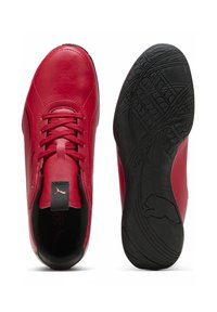 Baskets de sport rouges en cuir ; dotées d'une semelle en caoutchouc texturé noir, de lacets et d'un onglet avec le logo de la marque à l'arrière.