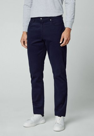 Chinos azul marino hechos de una mezcla de algodón, con un diseño de pierna recta, estilo de cinco bolsillos y cierre de botón metálico.