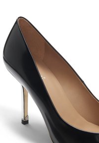 Black patent leather high heel with a pointed toe and a slim metallic silver heel, featuring a smooth inner lining and subtle branding detail.