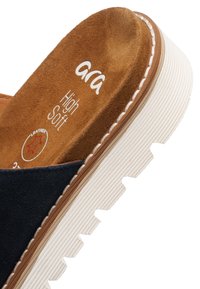 Brun ruskindsindersål med teksten "ara High Soft", navyblå øvre rem og hvid robust sål på en afslappet slip-on sko.