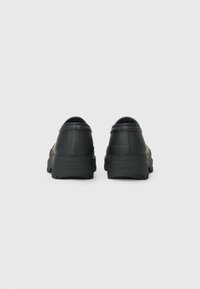 Black rubber shoes with a textured surface, rounded heel, and a thick, rugged sole, designed for durability and comfort.