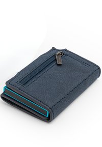 Portofel texturat de culoare bleumarin, cu un buzunar frontal cu fermoar și colțuri rotunjite, așezat pe o suprafață albă.