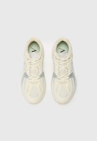 Sneakers with a cream mesh upper, silver accents, and white laces. Features a rounded toe and padded tongue, with a light green insole.