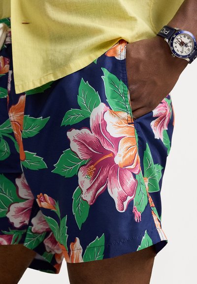 Colorful floral swim shorts featuring pink and orange hibiscus patterns on a navy background, with vibrant green leaves and a side pocket.