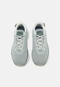 Svetlomodré tenisky Nike s mriežkovou textúrou, zaoblenou špičkou, bielymi šnúrkami a dekoratívnymi kruhovými akcentmi po stranách. Obsahujú mäkkú vnútornú podšívku.