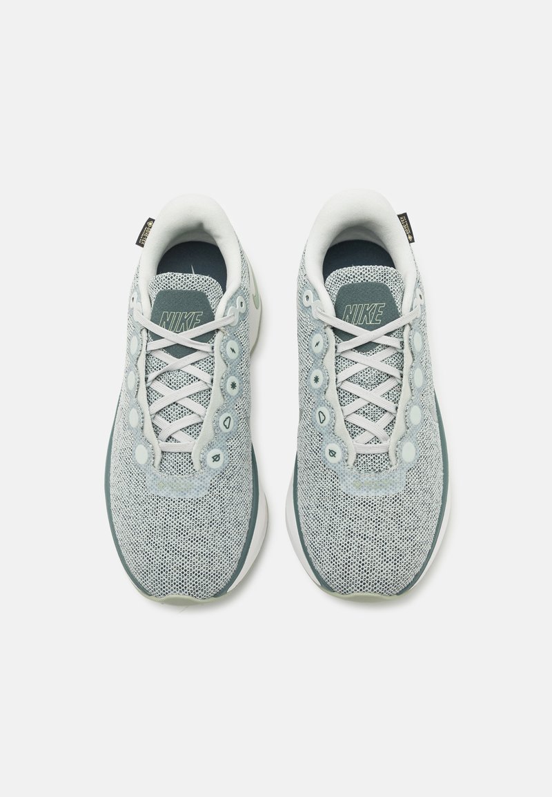 Helle blaue Nike-Sneaker mit Mesh-Struktur, abgerundeter Spitze, weißen Schnürsenkeln und dekorativen runden Akzenten an den Seiten. Mit weichem Innenfutter.