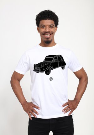 Bílá bavlněná tričko s černým lineárním výkresem vintage auta, zobrazující podrobné designové prvky a emblém pod ním.