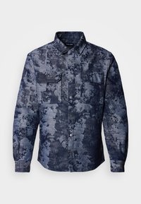 Denim shirt featuring a dark blue floral pattern, two chest pockets, button-up front, and a classic collar design. Textured fabric.