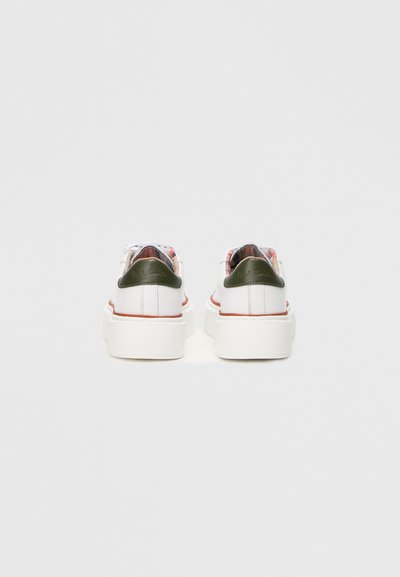 Valged sneakers paksu tallaga, roheliste kannakate aktsentidega ja värvikate mustritega voodriga, millel on valged kingapaelad ja minimalistik disain.