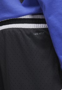 Short-sleeve blue shirt above black Dri-FIT shorts with a white elastic waistband. Shorts feature a textured, perforated fabric.