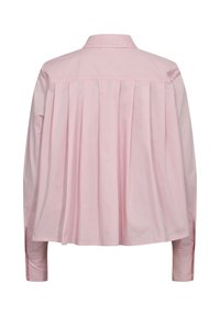 Chemise rose clair à manches longues avec des plis dans le dos et des poignets boutonnés, vue de dos sur fond blanc.