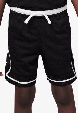 Sorte atletikshorts med hvid snor og hvid kant, båret af en person med mørk hud, vist fra livet til over knæene.