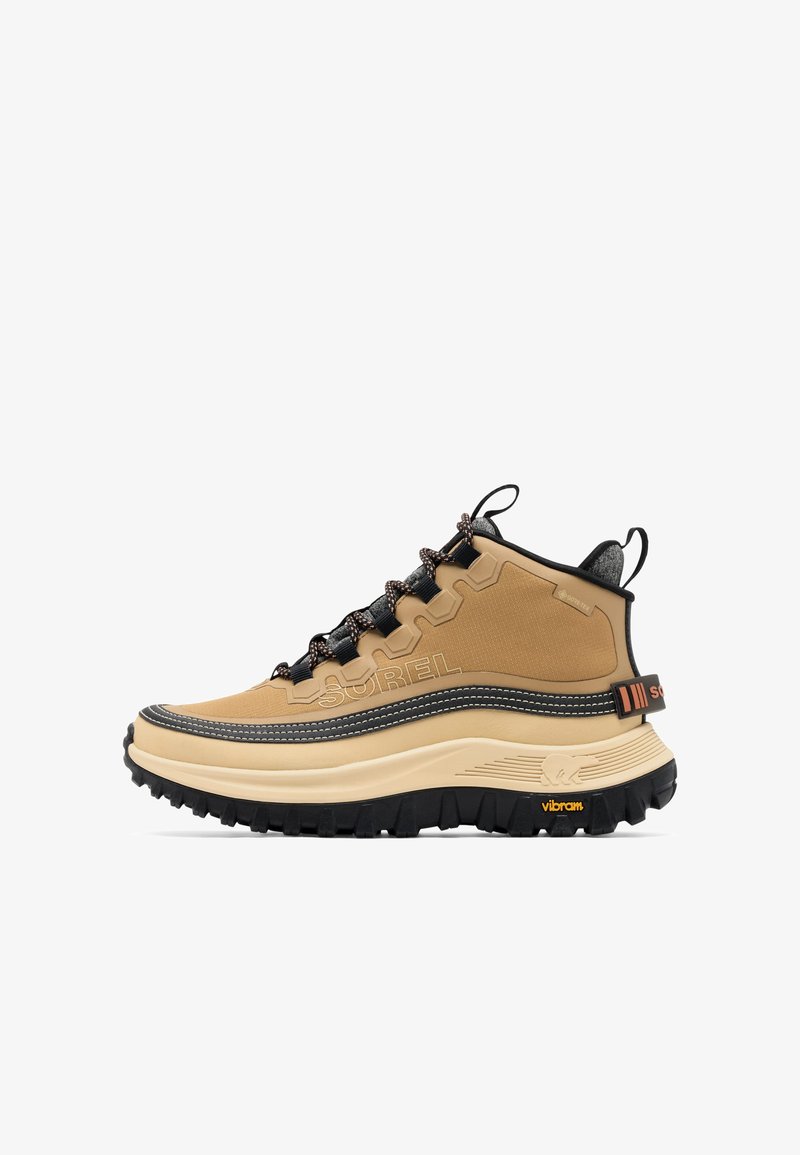 Botte de randonnée haute de couleur beige avec lacets noirs, semelle épaisse beige, semelle extérieure noire et robuste, et marquage "SOREL" sur le côté et la languette du talon.