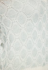 Maglione lavorato a maglia di colore azzurro chiaro con motivo a diamante, caratterizzato da una leggera scintillio. La morbida texture e il dettaglio a costine sull'orlo arricchiscono il design.