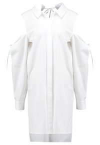 White long-sleeve shirt dress with cold shoulder cutouts and ties on sleeves, featuring a collar and concealed button placket down the front.