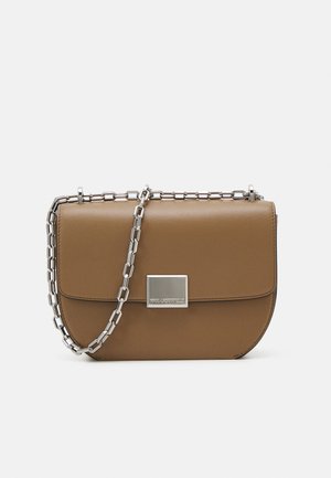 Bruine lederen crossbody tas met een gebogen vorm, zilveren kettingriem en een vierkante metalen sluiting aan de voorkant.