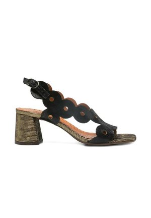 Sandalo nero con punta aperta, cinturini smerlati con ritagli circolari, fibbia regolabile alla caviglia e tacco a blocco dorato testurizzato.