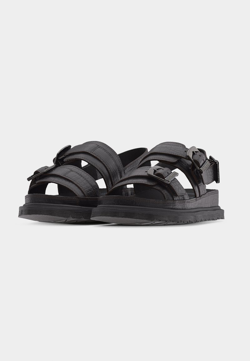 Black leather sandals with double buckle straps, textured sole, and open toe design, shown side-by-side on a plain white background.