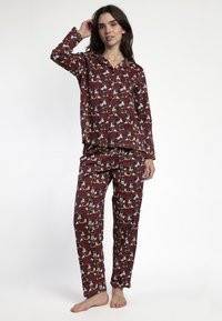 Conjunto de pijama en color malva con un patrón de juguetones personajes de dibujos animados en blanco, negro y amarillo. Tejido suave, mangas largas y pantalones sueltos.