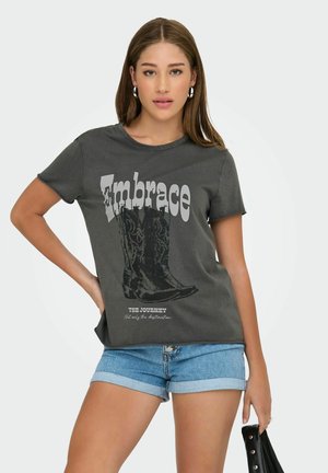Grijze katoenen t-shirt met een gedrukt cowboylaarzen-graphic en tekst "Omarm de Reis" in contrasterend wit. Korte mouwen, ronde hals.
