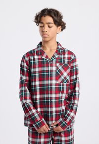 Red and green plaid pajamas with a button-up shirt, long sleeves, and a front pocket featuring a diagonal check pattern. Soft fabric texture.