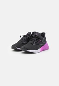 Par de zapatillas deportivas negras con suelas de degradado en rosa y blanco y logotipos de Reebok en rosa, mostradas una al lado de la otra sobre un fondo blanco.