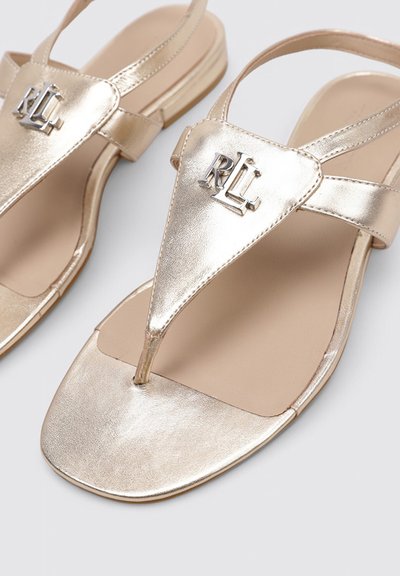 Sandales plates métalliques dorées avec design en tongs et logo RL sur la lanière supérieure, dotées d'une bride arrière et d'une forme carrée à l'avant.