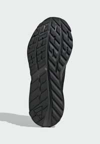 Čierna atletická podrážka so štruktúrovanou gumou, obsahujúca hlboké dezény a drážky pre trakciu. Trojuholníkový akcent pri päte.