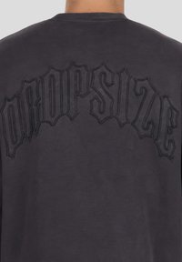 Ciemnoszara bluza z okrągłym dekoltem. Na plecach znajduje się duży, czarny haft "DROPSIZE" w gotyckiej czcionce. Miękka w dotyku.